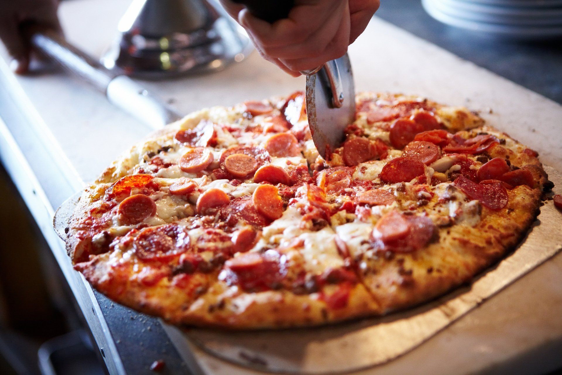 Fresh pepperoni pizza being sliced at Roma's Pizza